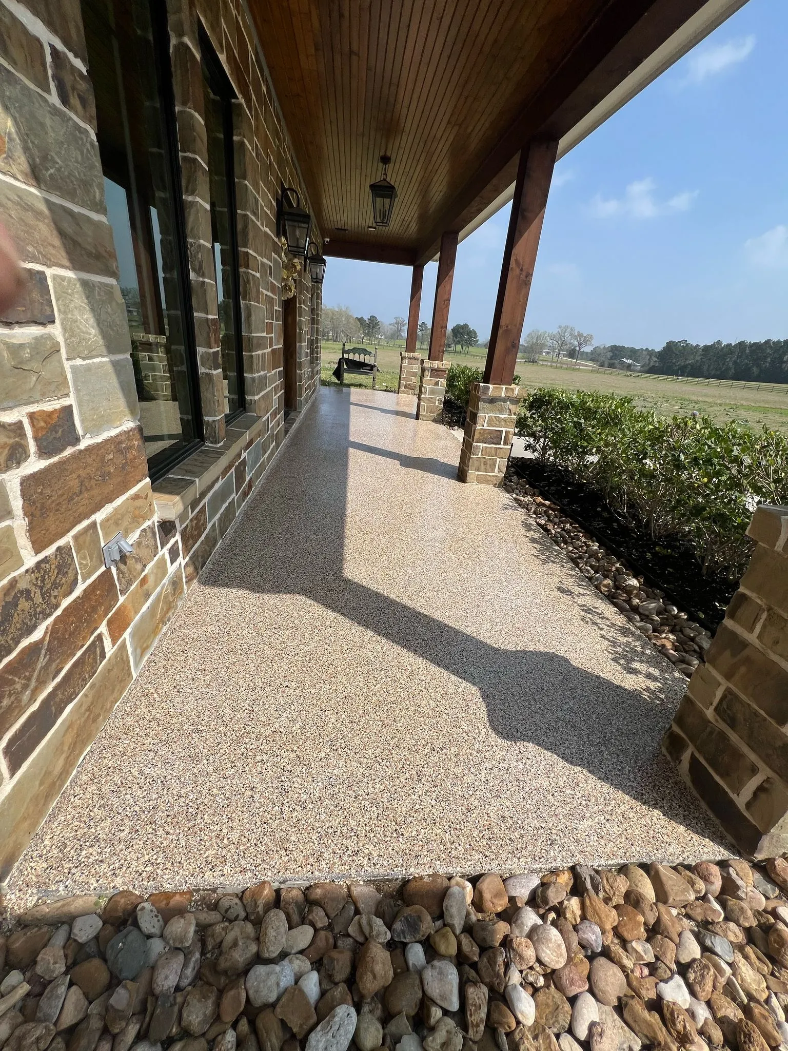 Tan flake coating on a covered patio beside a stone wall