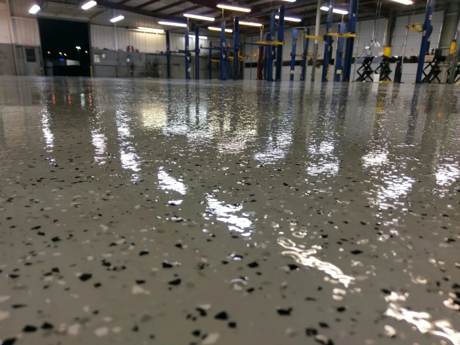 Glossy flake floor running down a vehicle shop past a row of two-post lifts