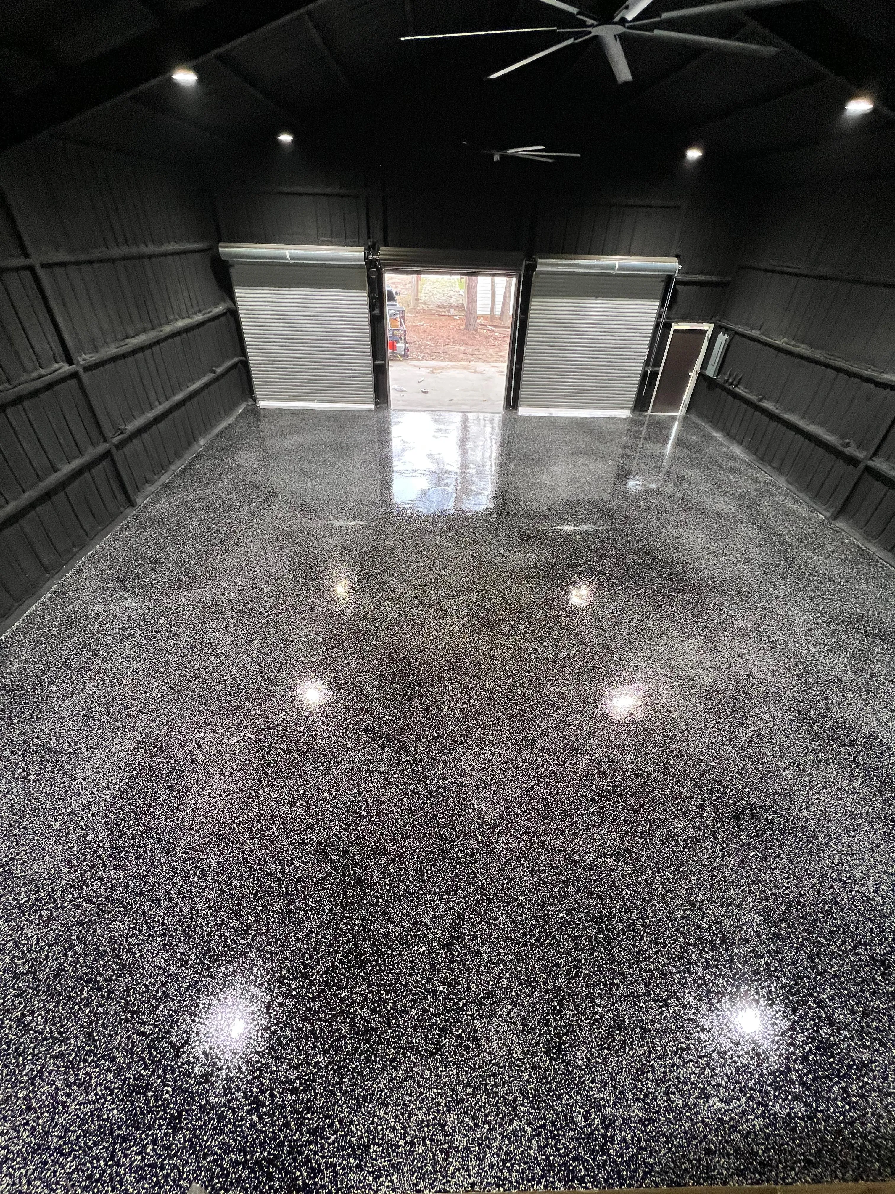 Full broadcast flake floor in a dark metal shop building, reflecting the ceiling lights